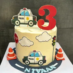 A fun police car themed cake for a 3rd birthday. This 1.5 kg Chocolate & Biscoff cake is decorated with edible traffic signs, clouds, and police cars for a delightful celebration.