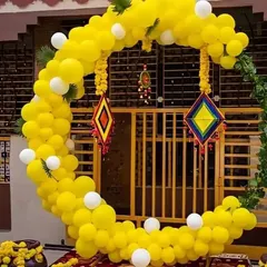 This outdoor Haldi setup features a large crescent-shaped balloon arch in yellow and white. I added traditional colorful hangings to the arch, blending modern balloon art with classic Indian decor elements.