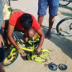 A father repairs his child's small bicycle, showing that repair skills are for everyone. It's a great way for parents to teach their kids about maintenance and self-sufficiency.