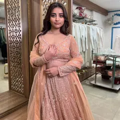 A close-up of the model in the peach lehenga, highlighting the intricate work on the full-sleeve blouse.