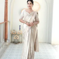 The epitome of understated elegance. This special tissue silk saree in a soft ivory is a masterpiece of light and texture. Paired with a fully hand-embroidered blouse covered in pearls and cutdana, this ensemble is crafted for the bride who desires a sophisticated and ethereal look for her reception or special event.