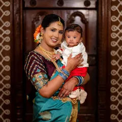 A mother, dressed in a stunning traditional saree, holds her newborn during their naming ceremony. This portrait captures the grace and love of new motherhood.