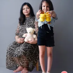 Big sister is excited to show off the new baby's shoes. This is a heartwarming way to include siblings in the maternity session and announce the coming arrival.