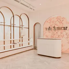 At Kate & Oscar, the customer journey begins at this welcoming reception desk. The curved form is set against a custom-illustrated backdrop, with arched clothing racks framing the space and hinting at the whimsical, gentle aesthetic of the store.