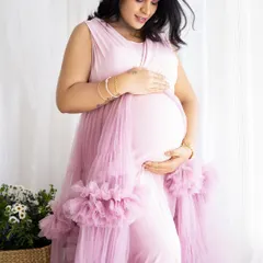 A gentle close-up of a mom-to-be cradling her bump, dressed in a lovely pink gown with ruffled details.