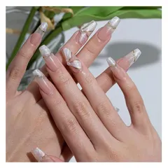 Ethereal and elegant, these long coffin nails feature a pearly white base with delicate 3D sculpted details, gold foil, and gold line accents for a truly artistic look.