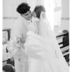 A candid black and white photograph capturing a sweet kiss on the cheek inside the church after the ceremony.