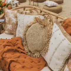 A close-up of the custom cushions, featuring a mix of textures like jute, seashells, and palm tree prints, perfectly capturing the rustic tropical vibe.