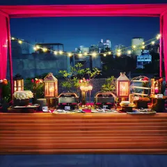 A stunning rooftop party setup against the city skyline. The warm string lights and elegant buffet create a magical ambiance for an unforgettable evening.