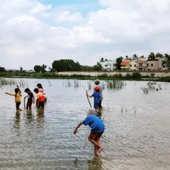 Wading into the water, children begin the process of harvesting clay, feeling the texture of the earth between their fingers and toes.