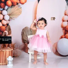 A girl stands proudly in a pink dress, surrounded by a modern and stylish balloon arch. This photo showcases a confident and happy personality.