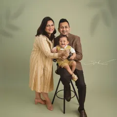 A picture of a happy family. This studio portrait shows the parents doting on their giggling baby, creating a memory of pure joy and togetherness.