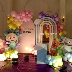 A pastel rainbow Cocomelon theme for a second birthday. This decoration includes a double rainbow arch, character cutouts, and a balloon mosaic number, creating a soft and dreamy party atmosphere.