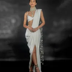A full-length shot from the Nikhil Thampi 'GLEAM' collection lookbook. The focus is on the elegant silhouette of the modern white saree, captured with clean studio lighting.