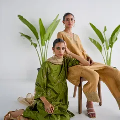 A dual-model shot for Esha Arora, showcasing two different colorways. The composition is balanced and clean, highlighting the elegant drape and embroidery of the ethnic ensembles.