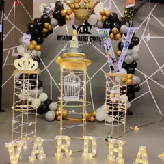 The complete setup for the dance studio's celebration. We used a circular balloon arch, lighted pedestals with decorative props, and large marquee letters spelling out the name 'VARDHA' on the floor.