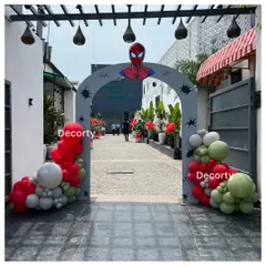 A Spider-Man themed entrance arch welcomes guests to the party. The arch is decorated with red, white, and green balloons and spider web details.
