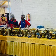 Our staff ready to serve at a wedding buffet. We offer a mix of veg and non-veg dishes, clearly labeled, so guests can choose according to their preference. The golden serving bowls add a touch of elegance.