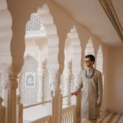 The groom looking sharp against the intricate jali work of the Anantara Jaipur, a perfect example of a royal groom portrait.