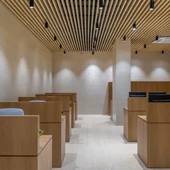 This perspective highlights the spacious layout and the effect of the lighting design. Spotlights are strategically placed to illuminate the workstations and the textured walls, creating a bright yet comfortable environment.