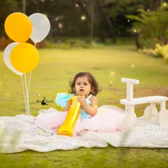 A classic first birthday portrait with balloons and a number '1' prop. This outdoor session for Hrutvi was set in a lovely green park.