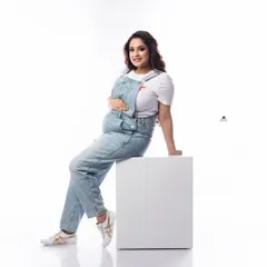 A fun and casual portrait of a mom-to-be in denim dungarees. This look is perfect for showing off a playful and relaxed personality during the maternity shoot.
