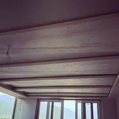 An in-progress shot of a false ceiling installation. This shows the structural framework for a coffered ceiling design before the final plaster and paint are applied, a key element in modern interior design.