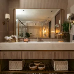 This master bathroom vanity is designed for both luxury and function. The warm wood cabinetry, white onyx countertop, and ample storage are complemented by elegant wall sconces and a large, simple mirror that makes the space feel expansive.