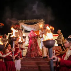 The bride's grand entry, guided by performers with torches. This dramatic entrance creates a powerful and unforgettable visual for your wedding album.