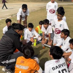 A coach sits with his team during a water break to discuss tactics and strategy. These moments of instruction are crucial for player development and team cohesion.