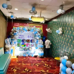 A wide view of the restaurant venue decorated for the elephant-themed first birthday, showing the main backdrop, seating area, and ceiling balloon bunches.