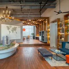 The Emaar Digi Homes experience center in Gurugram, designed with an industrial-chic aesthetic. Exposed ceilings, warm wood flooring, and a central architectural model create an engaging and informative environment for visitors.