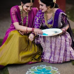 A candid shot of two friends sharing a laugh over a colorful rangoli. This photo captures the authentic, happy moments of a festival celebration.
