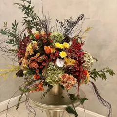 This design is inspired by poetry, for the sophisticated lover of art. It's a wild play of textures and densities in a palette of ochre, maroon, and golden brown, featuring ilex berry, hydrangea, and amaranthus.