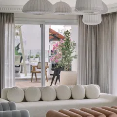 A view from the formal living room at Eden House out to the terrace balcony. The design ensures a seamless flow between the indoor and outdoor spaces, extending the living area.