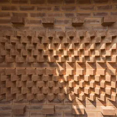 A textured wall created by projecting mud blocks in a wave-like pattern. This detail, designed for the Good Bricks Company office, is a playful exploration of the artistic possibilities of a simple brick.