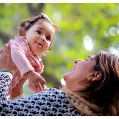 A playful moment between mother and daughter, captured outdoors. The natural background and genuine interaction make this portrait feel authentic and full of love.