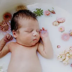 A peaceful and artistic newborn milk bath photo with delicate flowers. We offer unique and creative concepts for your baby's photoshoot.