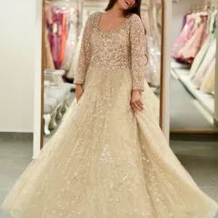 Feel like a star in this glittering gold ball gown. The full-length sleeves and sparkling tulle fabric create a look of pure opulence, perfect for a grand wedding reception.