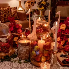 A wider view of the rustic, harvest-style tablescape. The design incorporates wooden elements, glass cloches, and whimsical giraffe figurines alongside the lush arrangements of flowers and fruit.