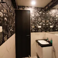 A bold bathroom revamp featuring a dramatic floral wallpaper on the upper half of the walls. The lower half has white textured tiles, and the geometric floor tiles add another layer of pattern, creating a high-contrast, modern look.