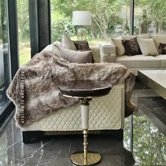 A detail from the Vasant Kunj glass house, showing a quilted leather sofa draped with a faux fur throw and a bespoke side table. This image captures the cozy, tactile elements we incorporate to make a space feel like home.