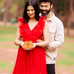 A sweet couple's portrait where they are holding a tiny pair of baby shoes together. This classic announcement pose is full of warmth and anticipation.
