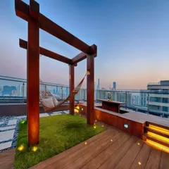 We design urban sanctuaries that offer an escape from the city bustle. This rooftop terrace project combines natural grass, warm wood, and ambient lighting to create a perfect relaxation spot, complete with a hammock overlooking the skyline.