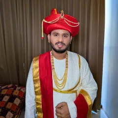 A close-up of the Maharashtrian groom's makeup. The focus is on a clean, bright look with the traditional tilak, complementing the vibrant red and gold of his attire.