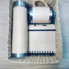 This is an example of a premium, 100% sustainable employee joining kit. It features a bamboo flask, mug, and notebook with a pen, all beautifully presented in a reusable cane grass basket, eliminating the need for plastic or cardboard packaging.