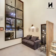 A cozy living area in the same 550 sq. ft. home. The massive floor-to-ceiling window brings in abundant natural light, while the wooden slat partition adds a touch of warmth and separates the staircase.