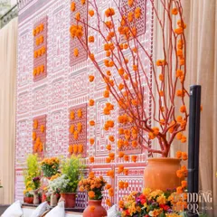 A stunning backdrop wall featuring a custom-printed design inspired by heritage architecture. The wall is accented with 3D panels and marigold clusters, with a beautiful manzanita tree centerpiece.