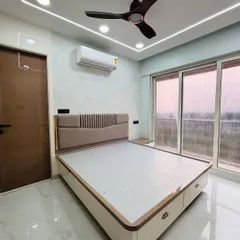 A peaceful and bright bedroom featuring a custom bed with a cushioned headboard and built-in drawers. The room is finished with elegant ceiling strip lighting and has a great view from the large window.