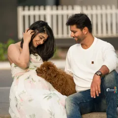 A relaxed and happy photo of the couple sitting together with their furry friend, showcasing a perfect family portrait.